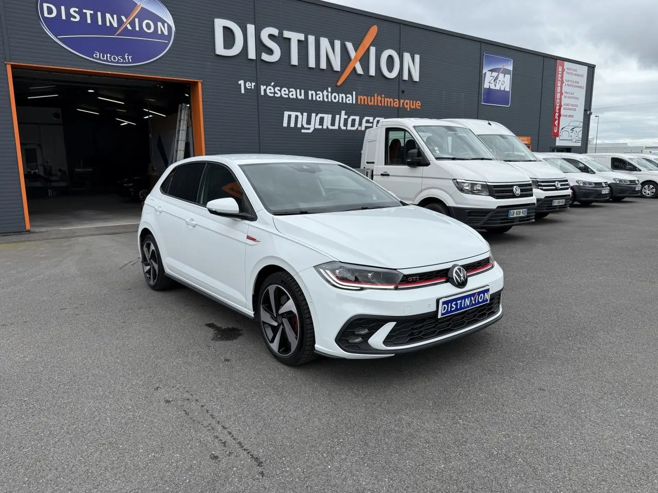 Volkswagen Polo GTI blanc pur vue 3/4 avant droit, avec jantes sport et calandre rouge distinctive.