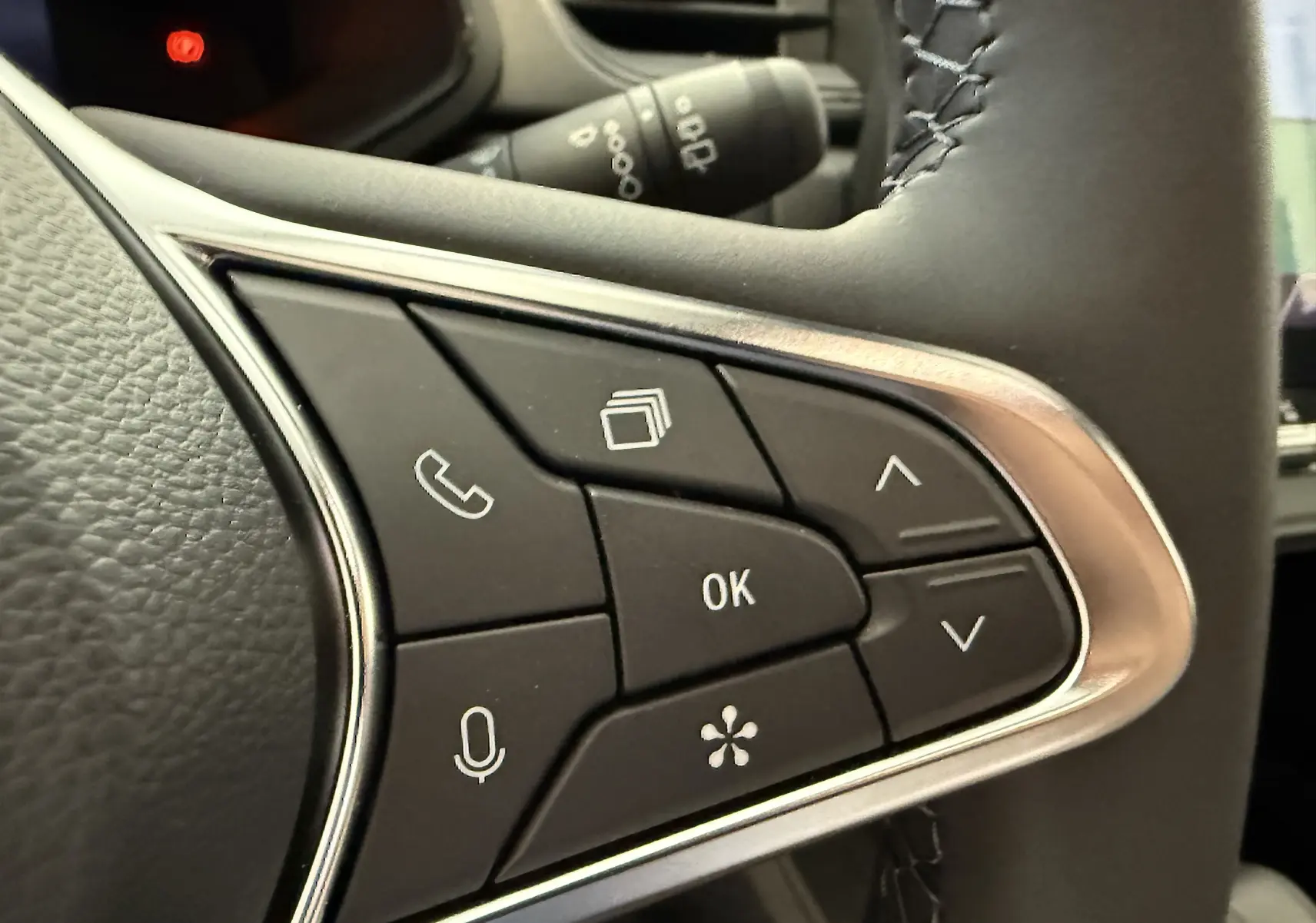 Gros plan sur les commandes multifonctions noires avec contour argenté du volant du Renault Captur gris Cassiopée 2025.