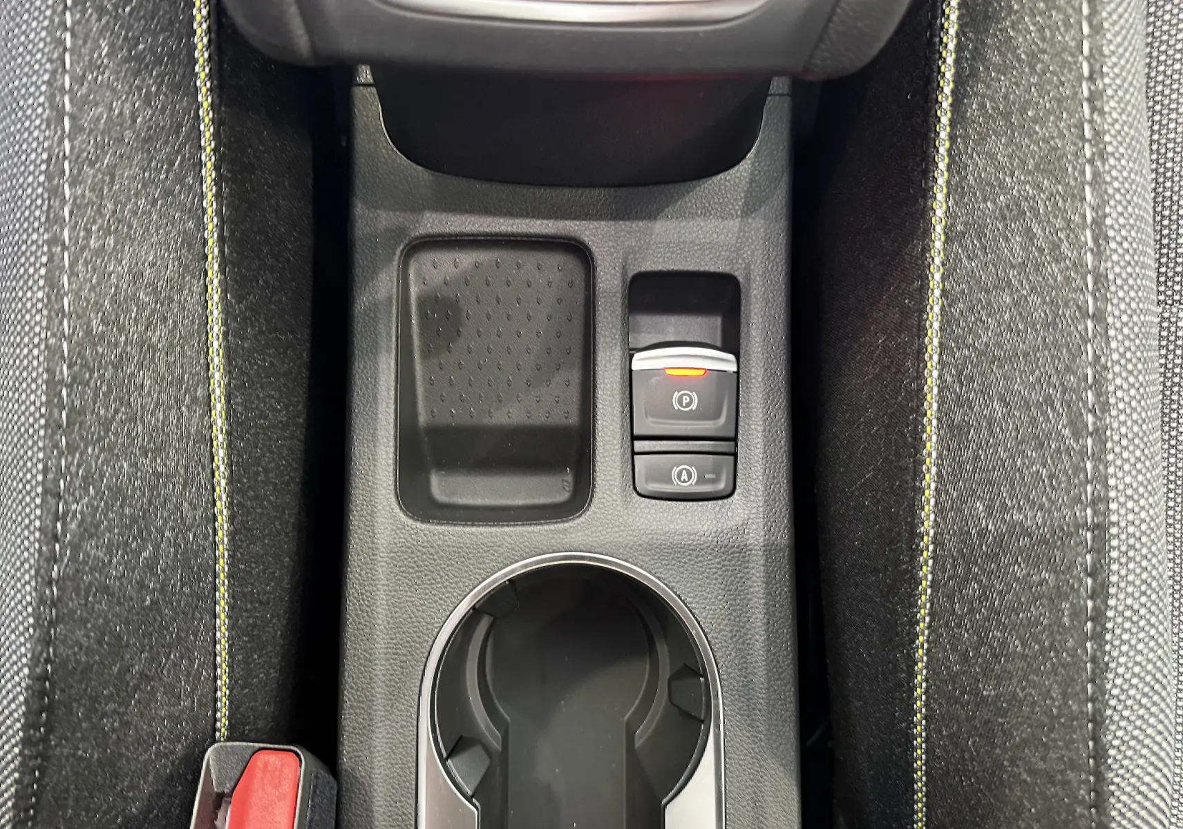 Vue en plongée sur la console centrale noire du Renault Captur gris, avec porte-gobelet et commandes électroniques visibles.