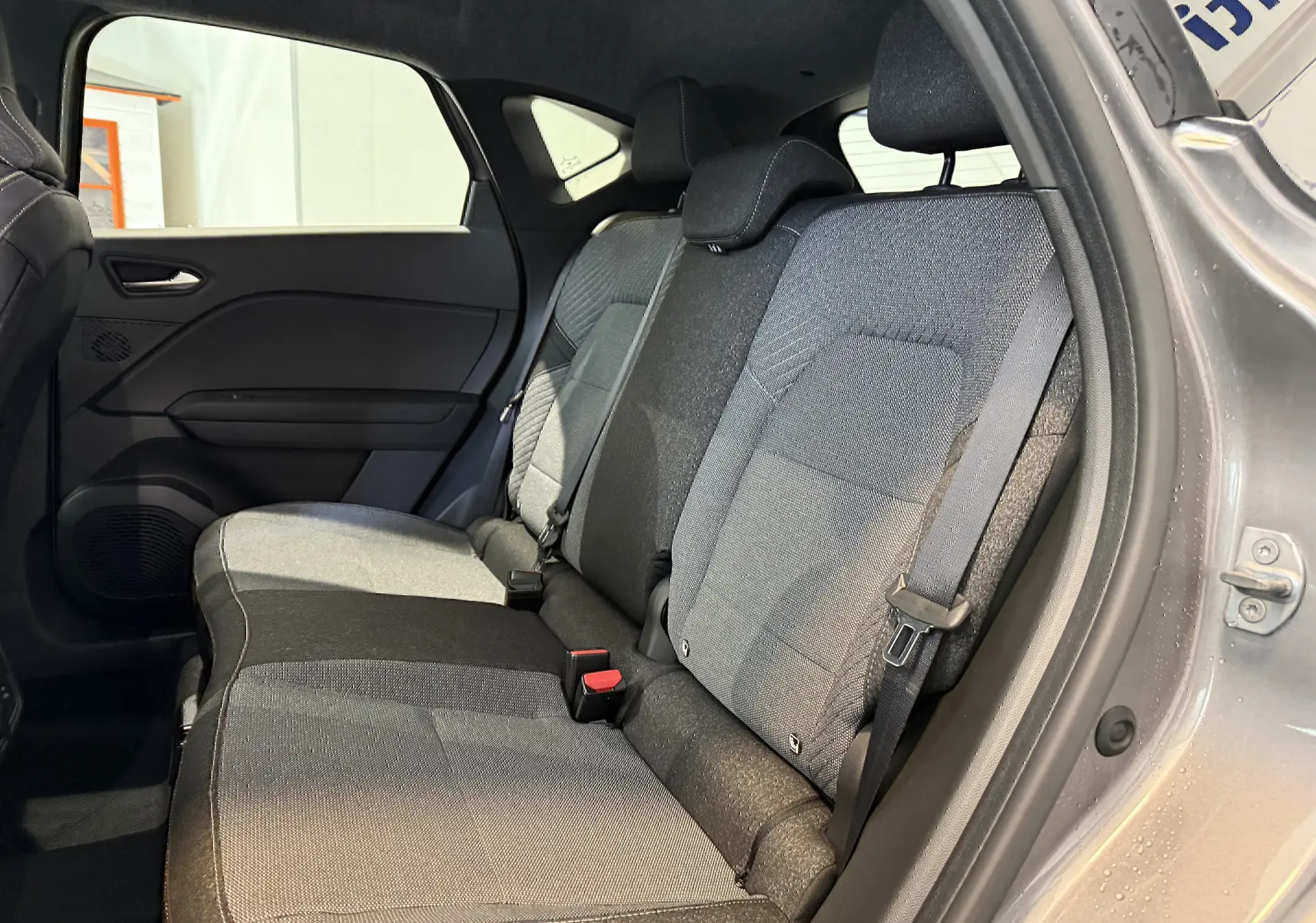 Vue intérieure côté droit des sièges arrière gris du Renault Captur 2025 hybride avec porte ouverte.