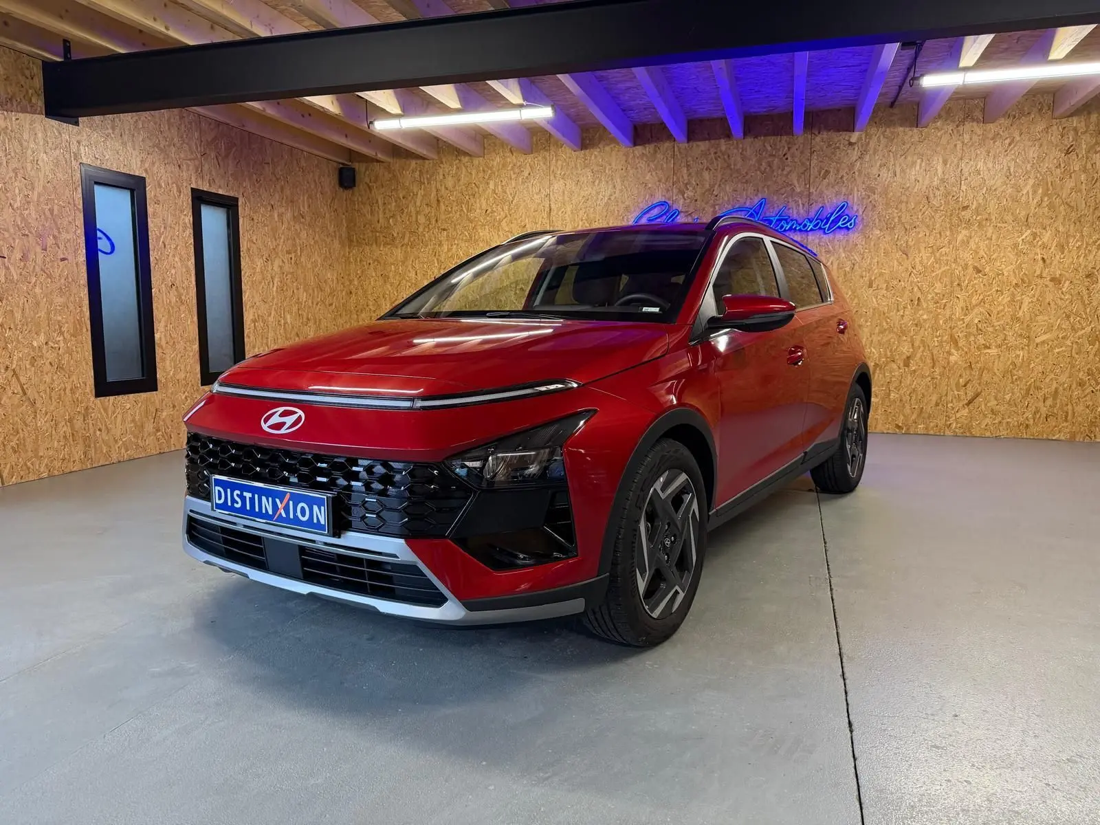 Vue 3/4 avant d'une Hyundai Bayon rouge avec calandre noir laqué et jantes alu 17 pouces dans un showroom.