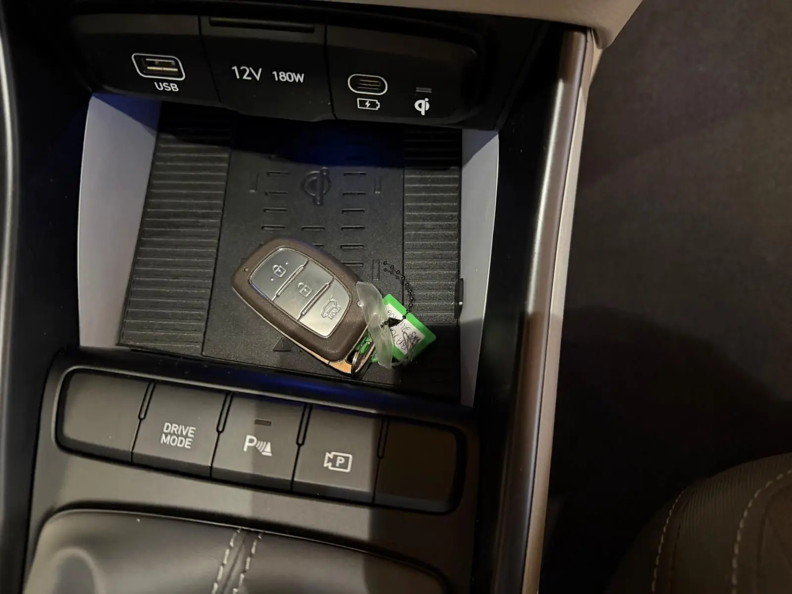 Gros plan sur la console centrale de la Hyundai Bayon rouge 2025, avec clé, boutons Drive Mode et aide au parking.