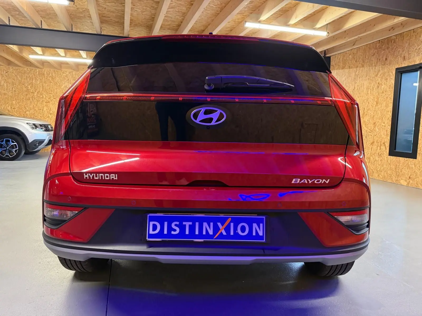 Vue arrière d'un Hyundai Bayon rouge avec calandre noir laqué et feux arrière LED dans un garage.