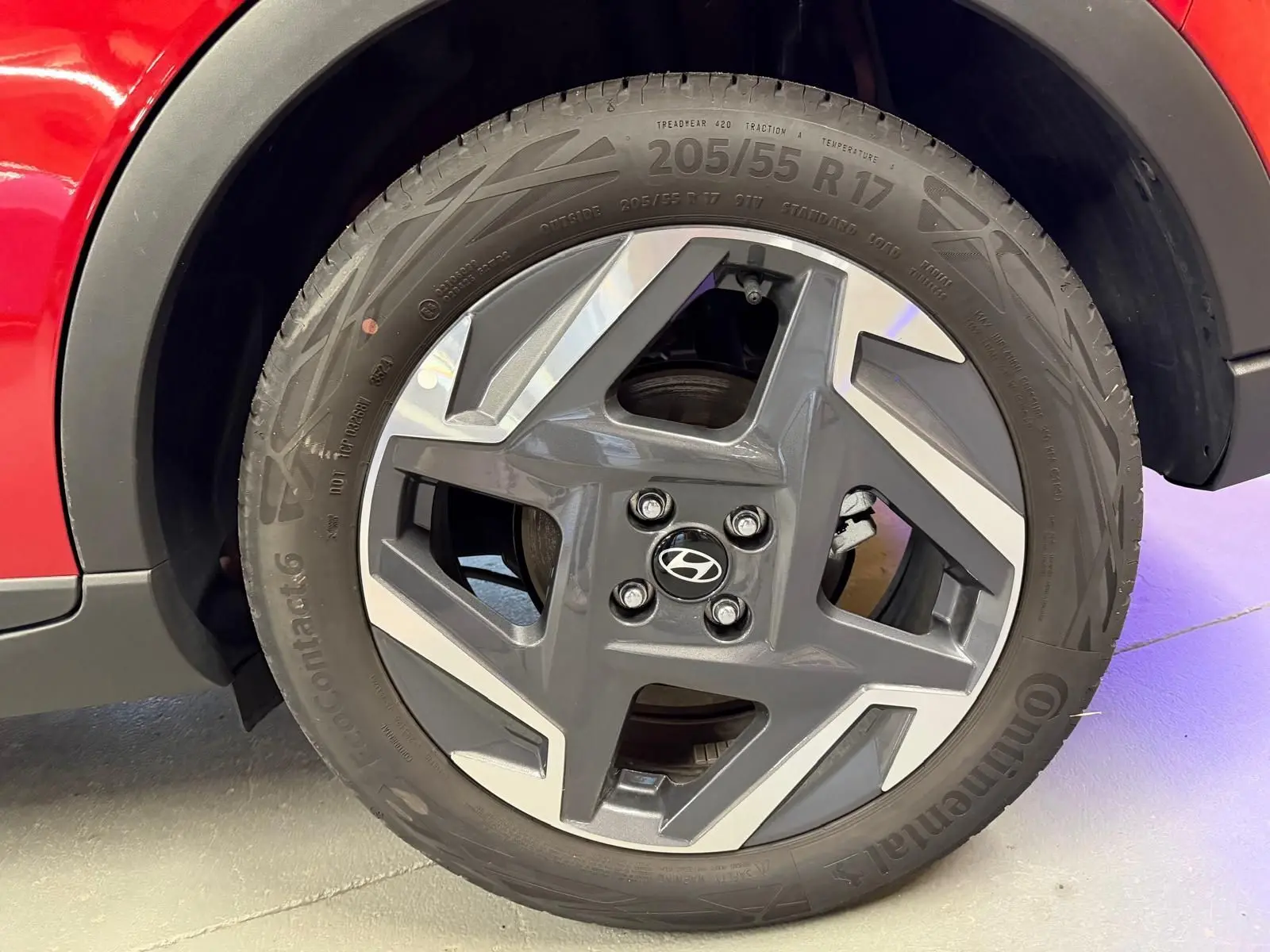 Gros plan sur la jante alu 17'' gris foncé avec inserts argentés du côté gauche d'une Hyundai Bayon rouge.