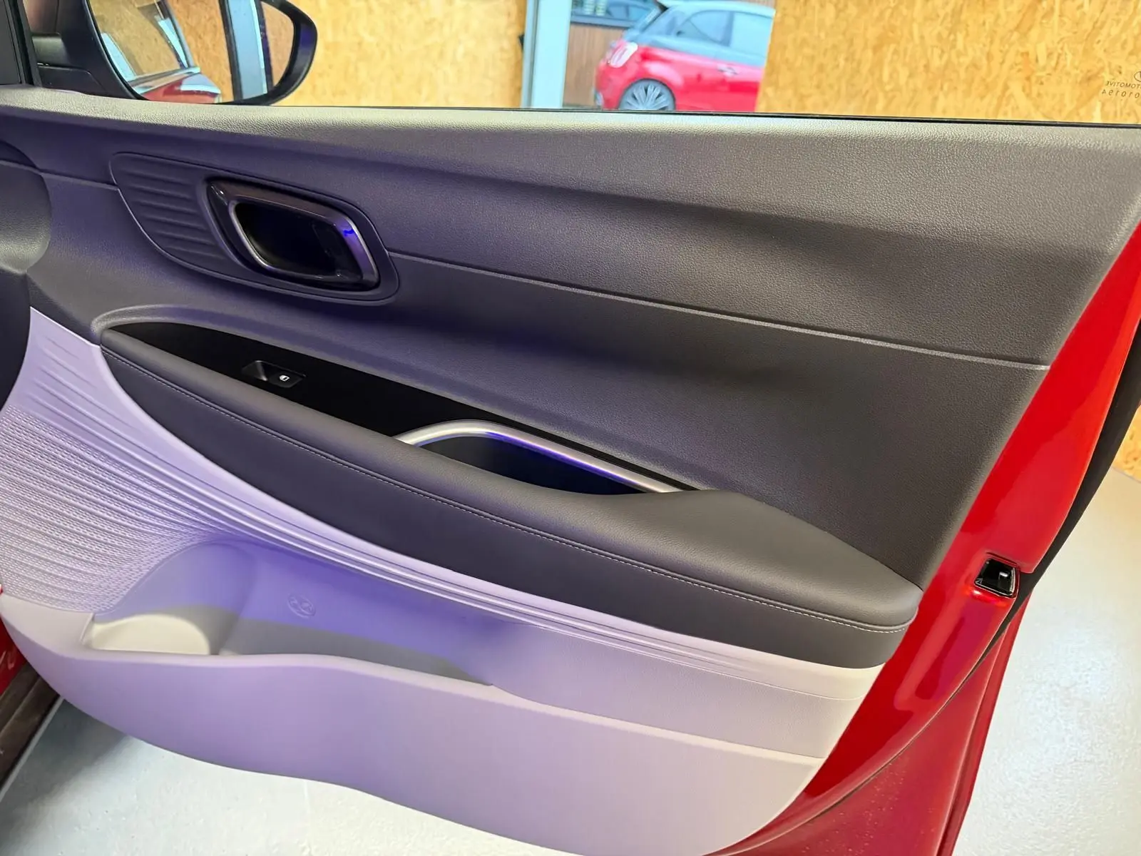 Vue rapprochée de la porte avant gauche rouge de la Hyundai BAYON 2025 avec intérieur bi-ton noir et gris clair.