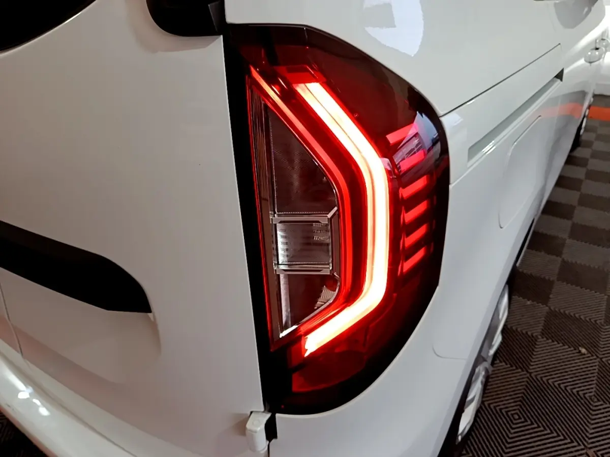 Gros plan sur le feu arrière droit rouge allumé du Renault Kangoo blanc, version Equilibre 2022, vue en angle arrière.