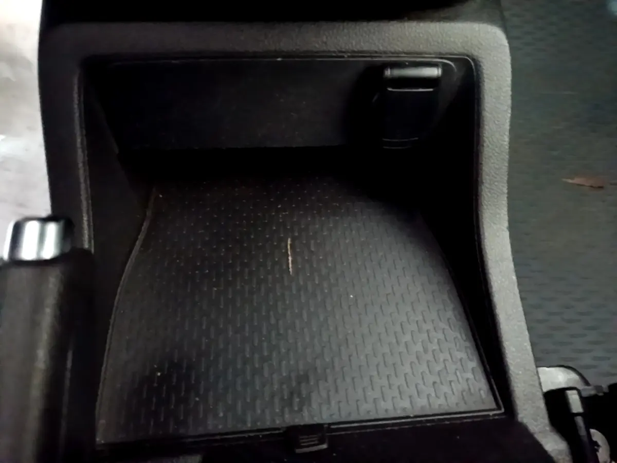 Gros plan sur le rangement central noir du Renault Kangoo blanc, version Equilibre Blue dCi 95, avec levier de frein à main visible.