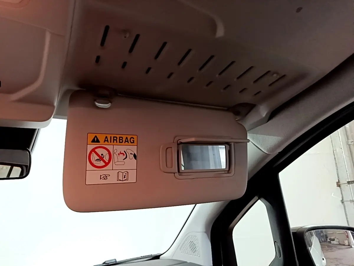 Détail de pare-soleil côté conducteur avec miroir intégré et avertissement airbag dans un Renault Kangoo blanc 2022.
