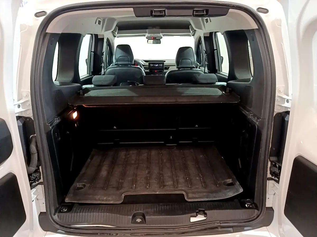 Vue arrière du coffre ouvert du Renault Kangoo blanc 2022, montrant l’espace de chargement et les sièges arrière rabattus.