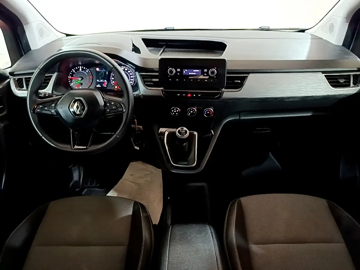 Vue intérieure frontale du tableau de bord du Renault Kangoo blanc 2022 avec volant multifonctions et boîte manuelle.