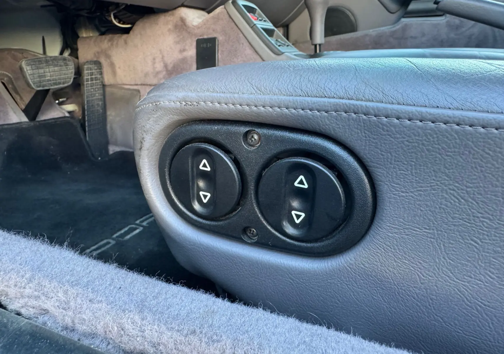 Gros plan sur les commandes électriques du siège en cuir gris polaire côté conducteur d'une Porsche 911 Carrera 993 de 1996.