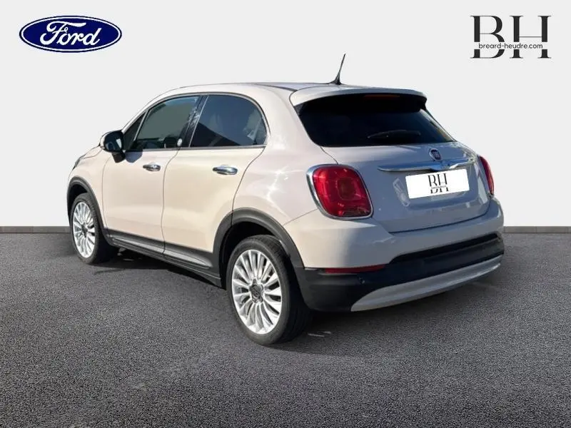 Vue 3/4 arrière droite d'une FIAT 500X argentée avec jantes alu et lunette arrière surteintée.