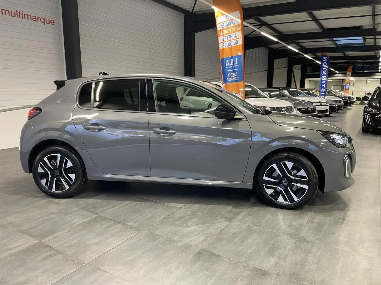 Peugeot 208 gris selenium vue de profil côté gauche, avec jantes alliage bi-tons et rétroviseurs noirs brillants.