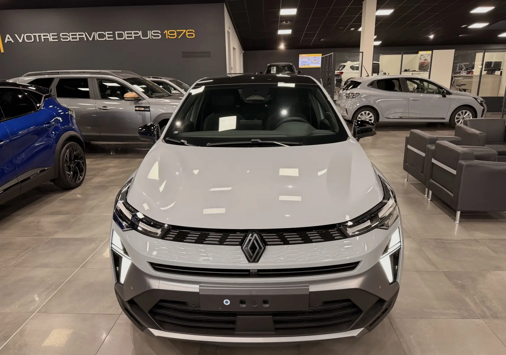 Vue avant du Renault SYMBIOZ gris Rafale en showroom, mettant en valeur sa calandre moderne et ses feux LED distinctifs.