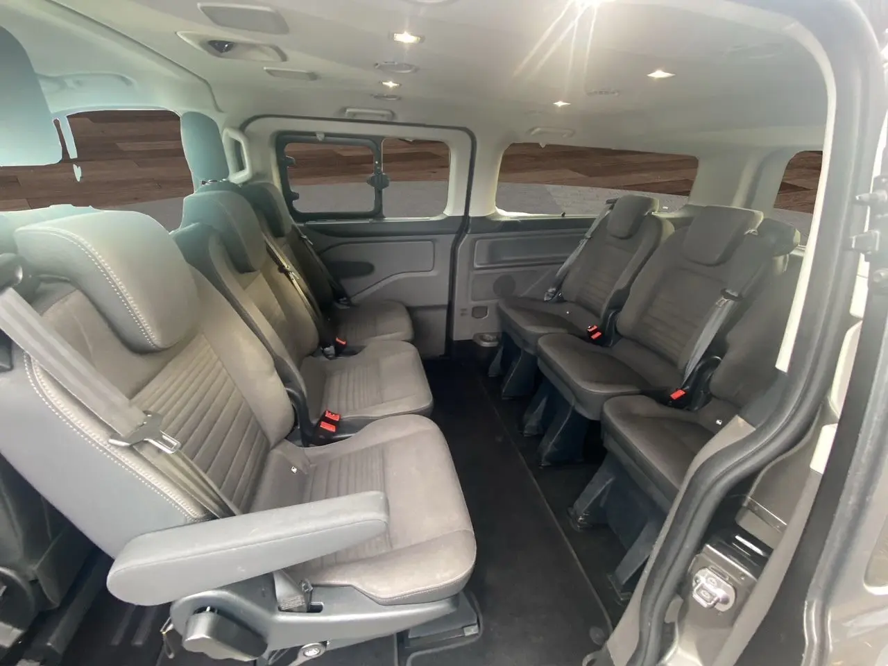 Intérieur du Ford Tourneo Custom gris magnetic, vue latérale droite sur les sièges passagers en rangées face à face.
