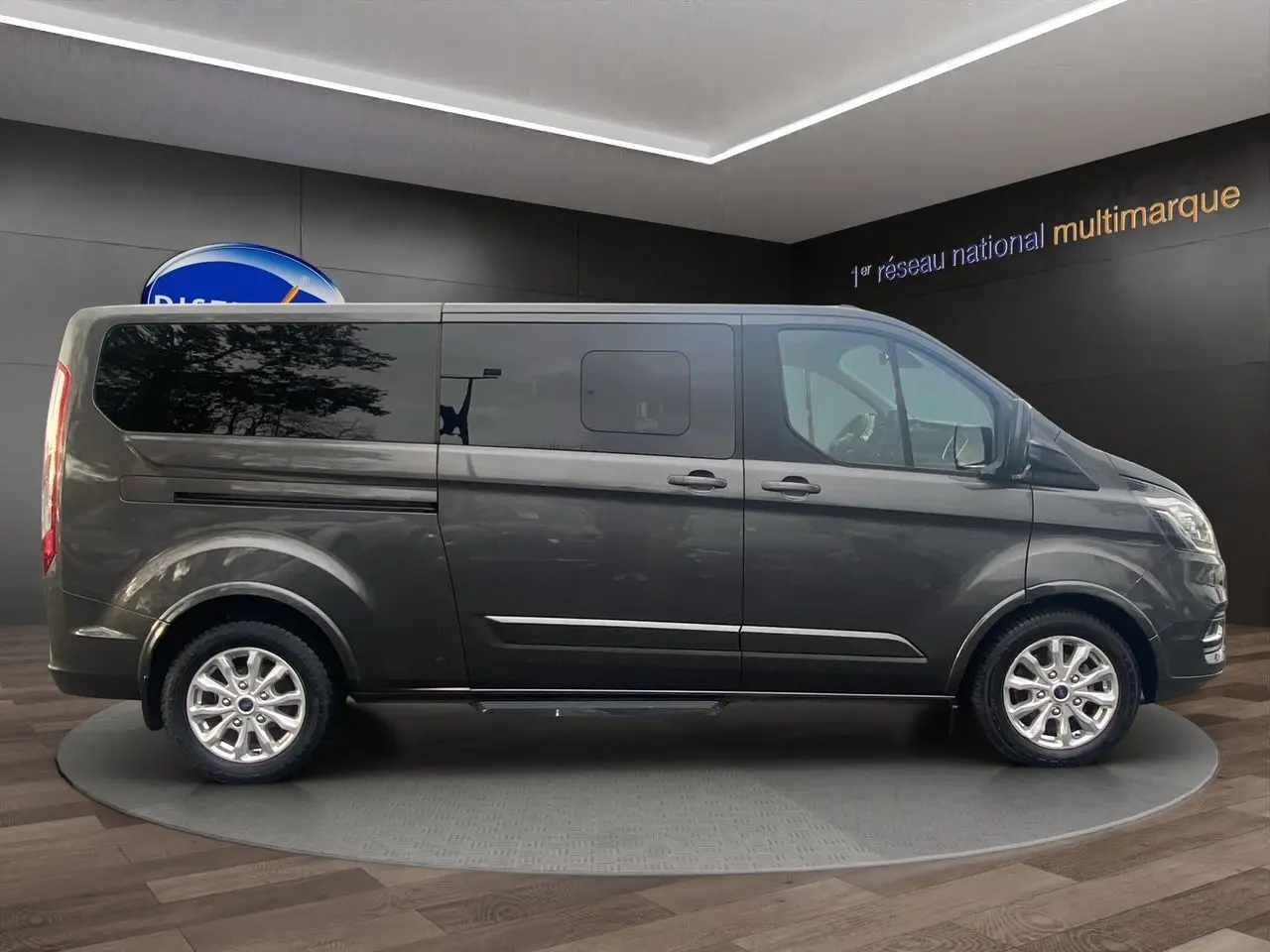 Ford Tourneo Custom gris magnetic vu de profil côté gauche, avec vitres teintées et jantes alliage.