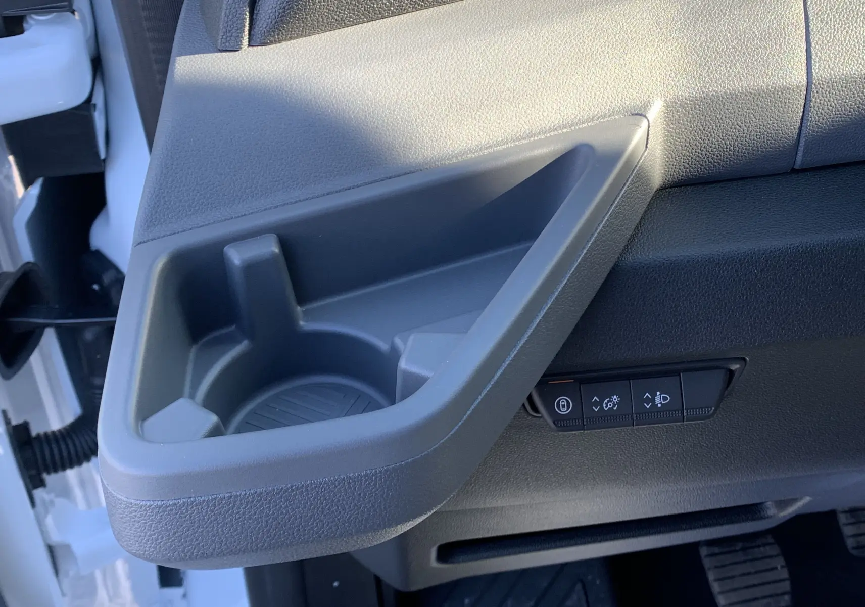 Gros plan sur le rangement latéral gris et les commandes d'éclairage côté conducteur du Renault Master blanc 2025.