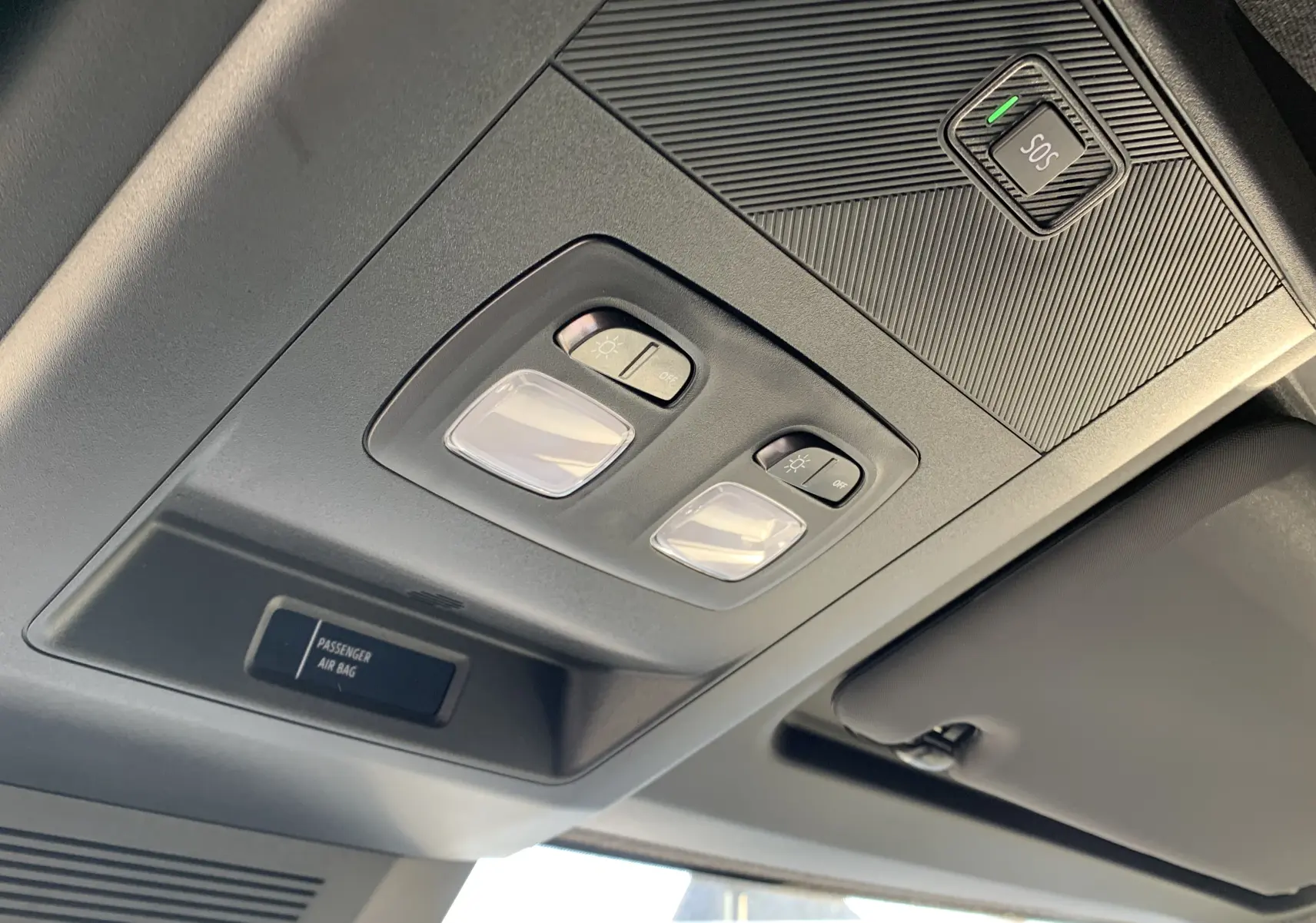 Plafonnier intérieur avec commandes d'éclairage et bouton SOS du Renault Master blanc, vue en contre-plongée côté conducteur.