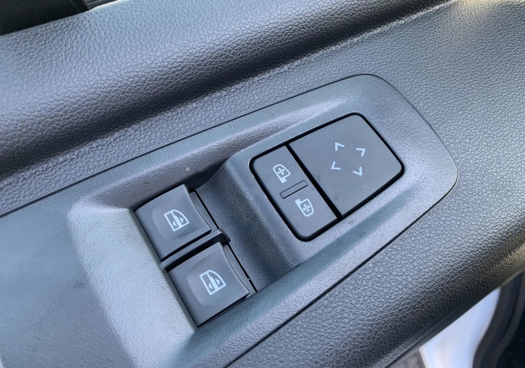 Gros plan sur les commandes de réglage des vitres et des rétroviseurs du côté gauche d’un Renault Master blanc.