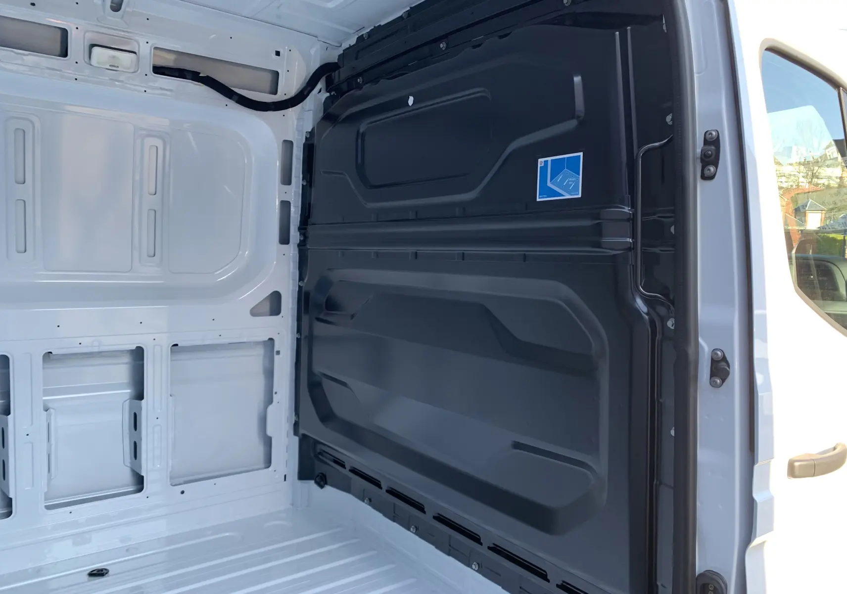 Intérieur du coffre blanc mine du Renault Master 2025, vue latérale droite avec cloison noire séparatrice visible.