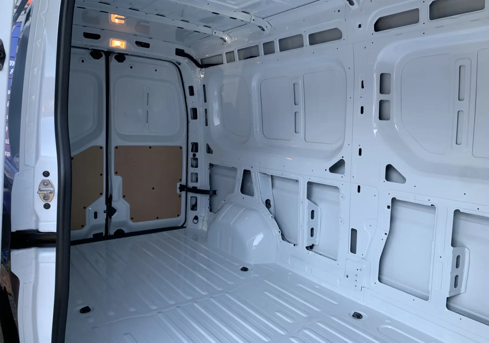Intérieur du Renault Master blanc mine 2025 vu de l'arrière, montrant la zone de chargement vide et éclairée.
