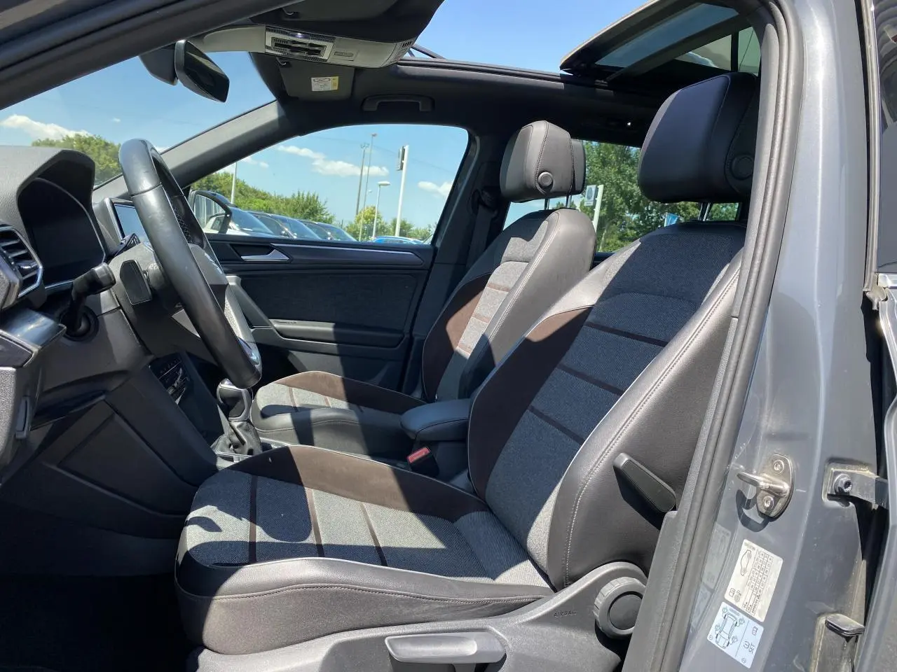 Intérieur du SEAT Tarraco gris dauphin vu côté gauche, sièges tissu gris et Alcantara, toit ouvrant panoramique ouvert.