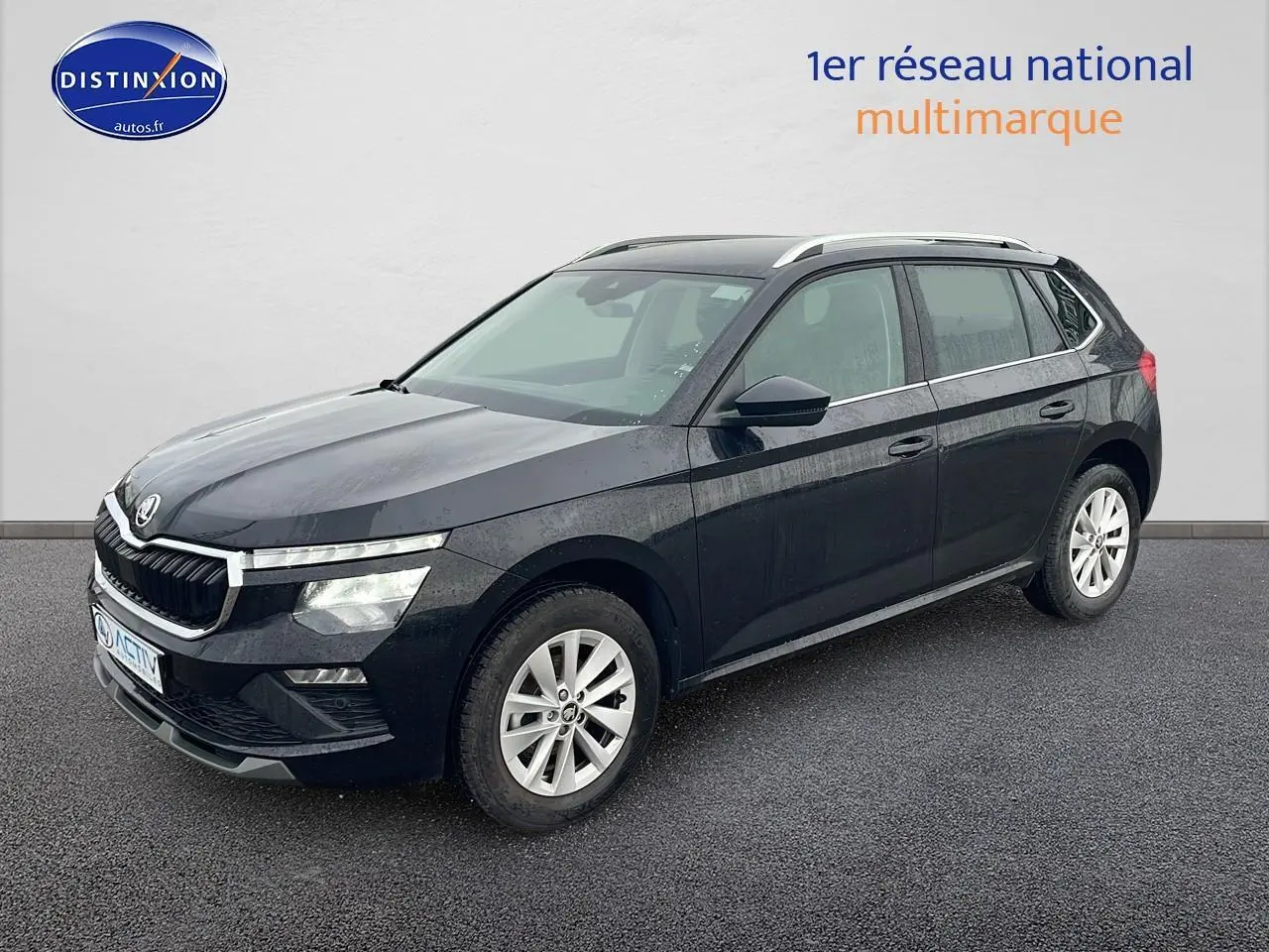 Vue 3/4 avant d'un Skoda Kamiq noir 2025 avec calandre chromée et jantes alu sur sol gris.