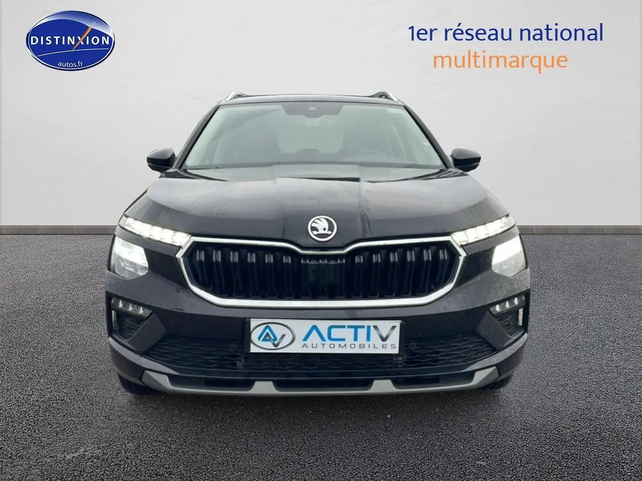 Vue frontale d'un Skoda Kamiq noir avec calandre chromée et feux LED allumés sur fond neutre.