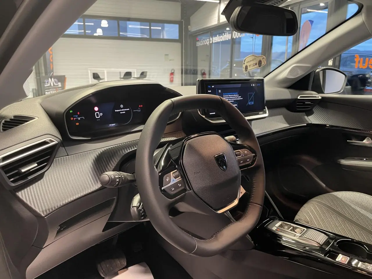 Vue intérieure du poste de conduite de la Peugeot 208 noire, avec volant compact et écran tactile central.