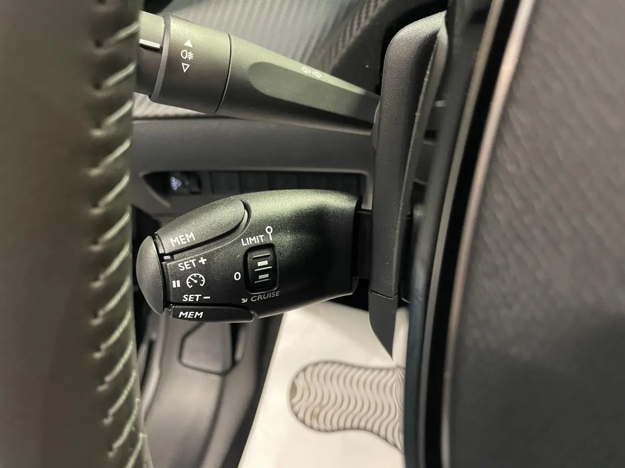 Gros plan sur la commande de régulateur de vitesse noire dans l'habitacle d'une Peugeot 208 hybride 2025.