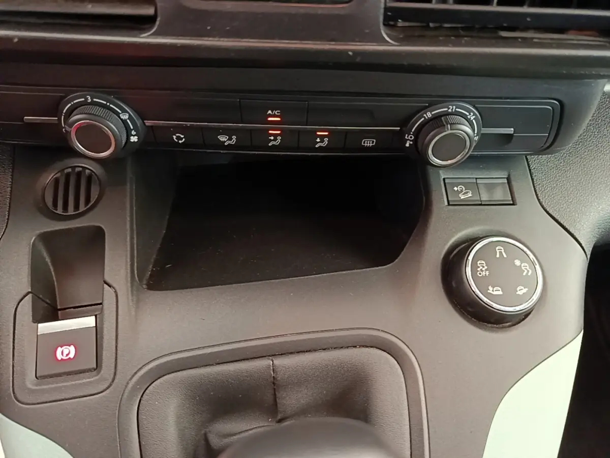 Gros plan sur la console centrale noire du Citroën Berlingo 2022, montrant les commandes de climatisation et frein à main électrique.