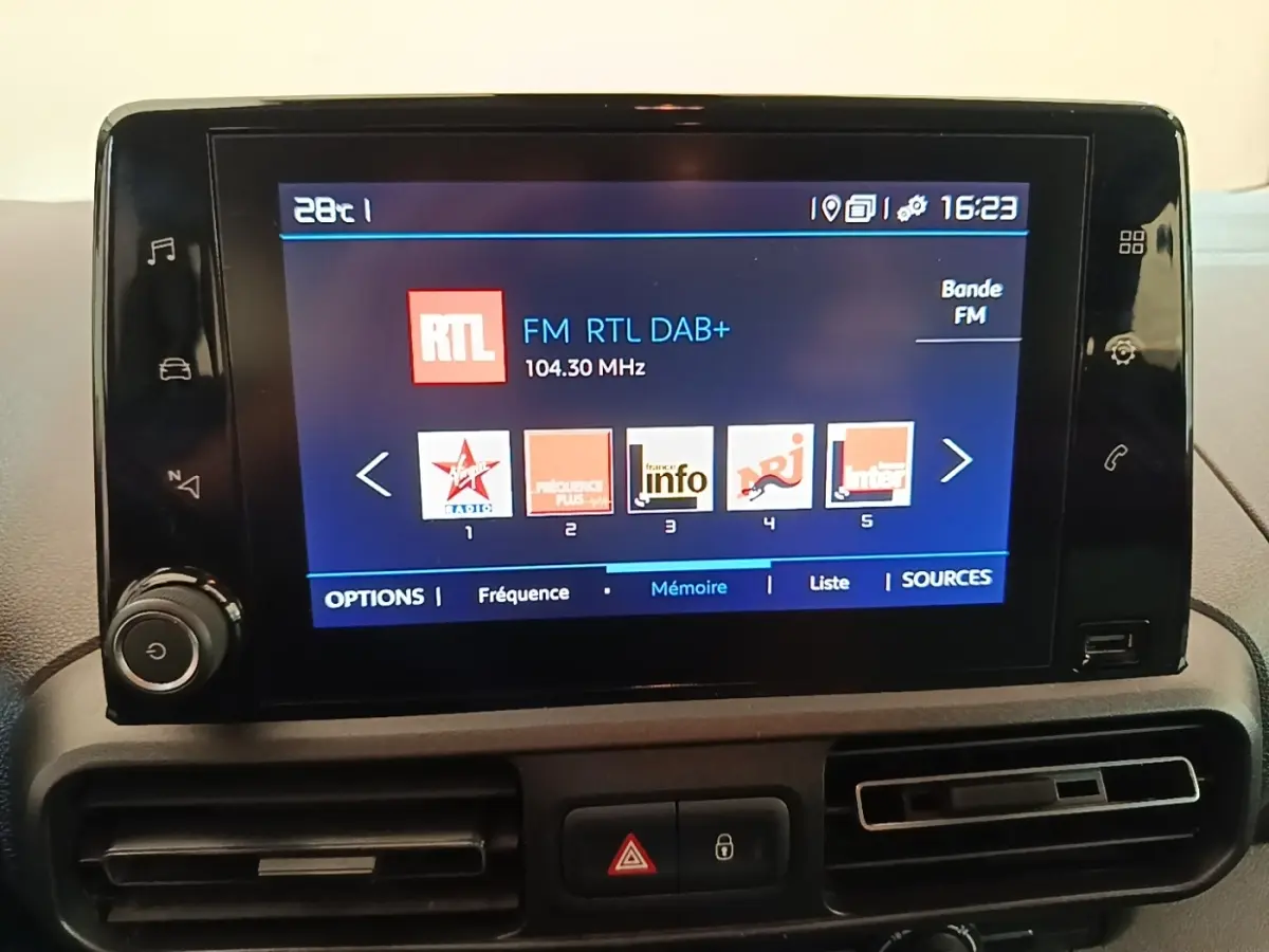 Écran tactile central affichant les stations radio dans l'habitacle du Citroën Berlingo blanc, vue de face.
