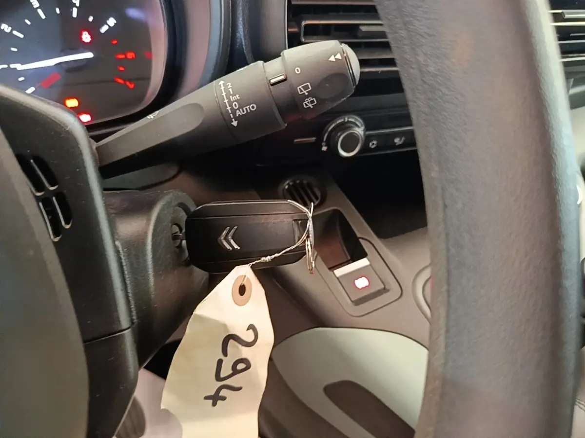 Gros plan intérieur sur le volant noir et la clé de contact du Citroën Berlingo blanc, avec tableau de bord partiellement visible.