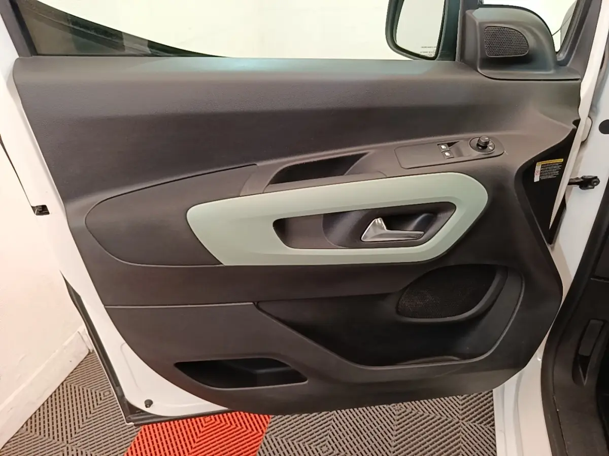 Vue rapprochée de la porte avant gauche blanche du Citroën Berlingo 2022 avec garniture intérieure noire et poignée grise.