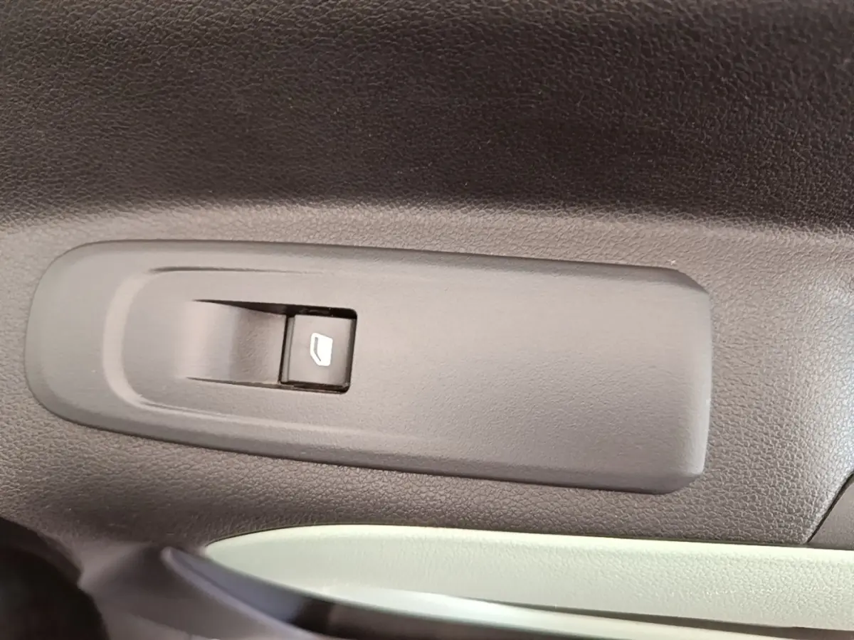 Gros plan sur l'interrupteur de lève-vitre côté conducteur dans l'habitacle noir et gris du Citroën Berlingo blanc.
