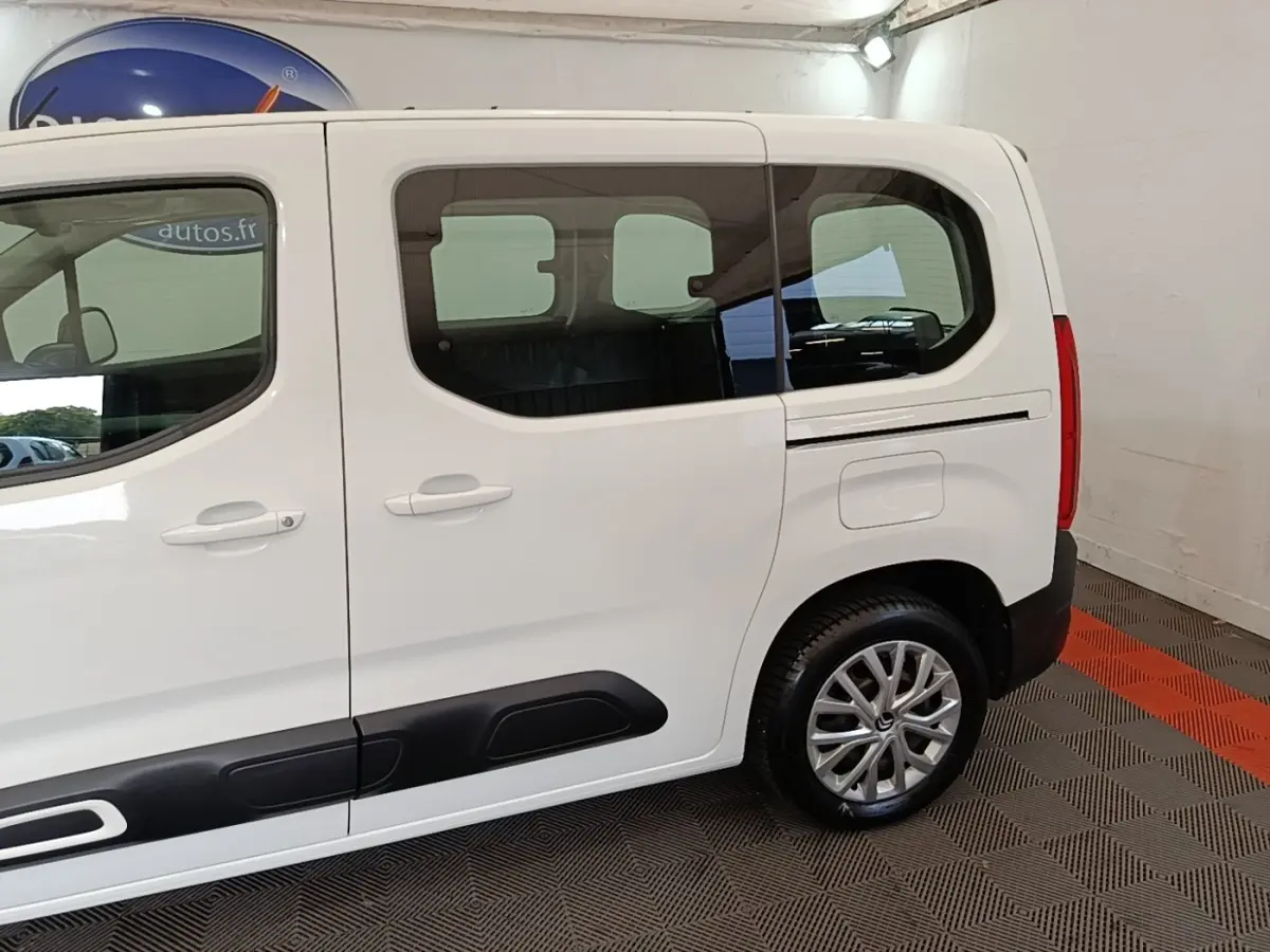Vue latérale droite d'un Citroën Berlingo blanc 2022 avec protections noires sur les portières et jantes alliage.