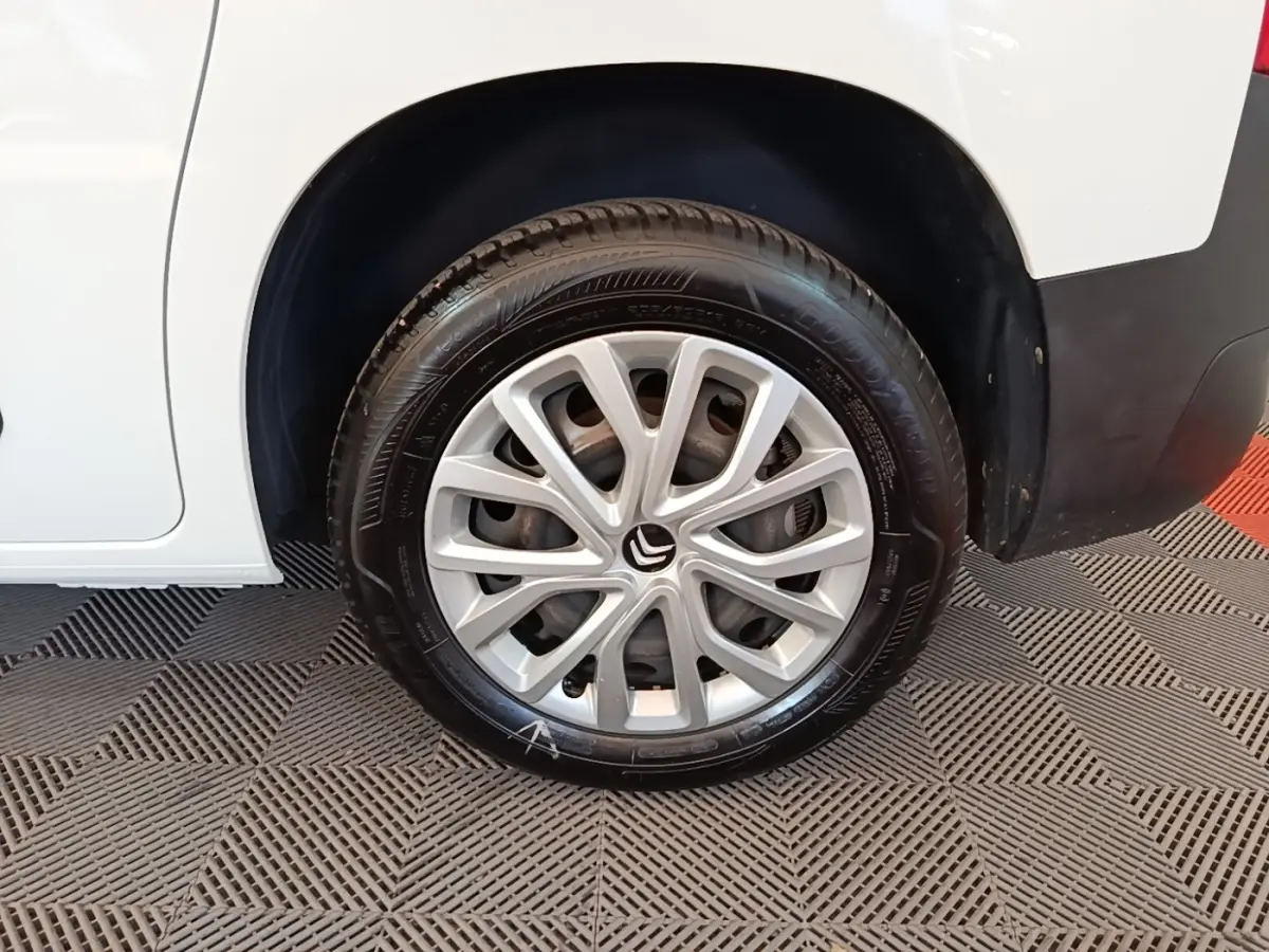 Gros plan sur la roue arrière droite d'un Citroën Berlingo blanc avec jante alliage et logo Citroën visible.
