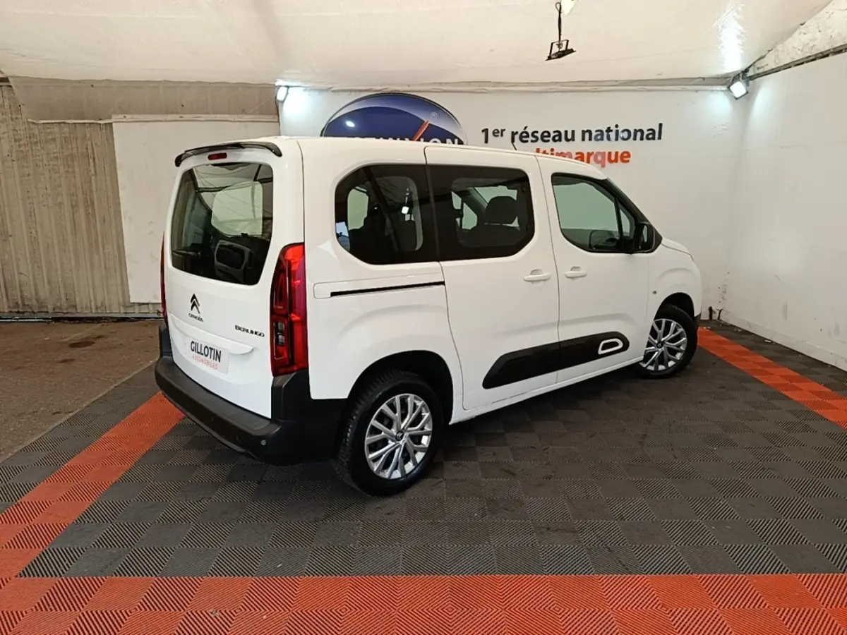 Vue 3/4 arrière droite d'un Citroën Berlingo blanc avec protections latérales noires et jantes alliage.