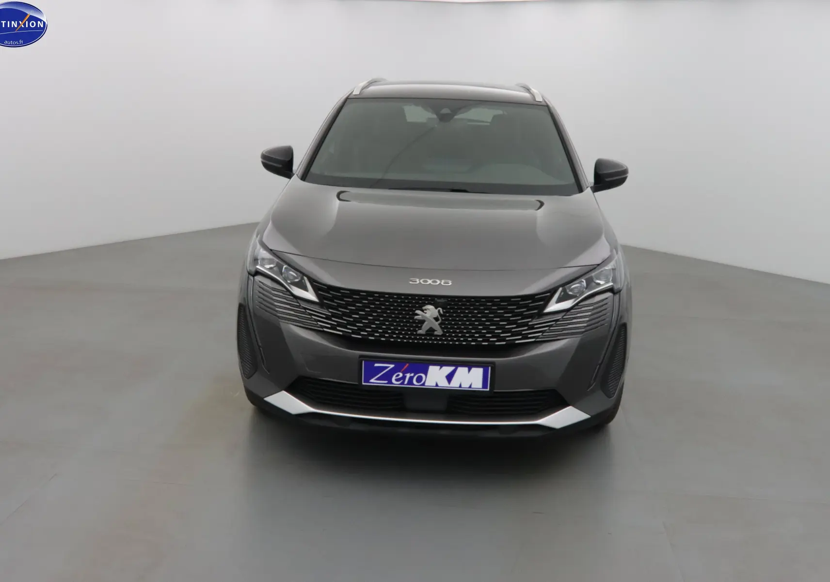 Peugeot 3008 gris platinium métal vue de face dans un studio, mettant en valeur sa calandre distinctive et ses phares LED.