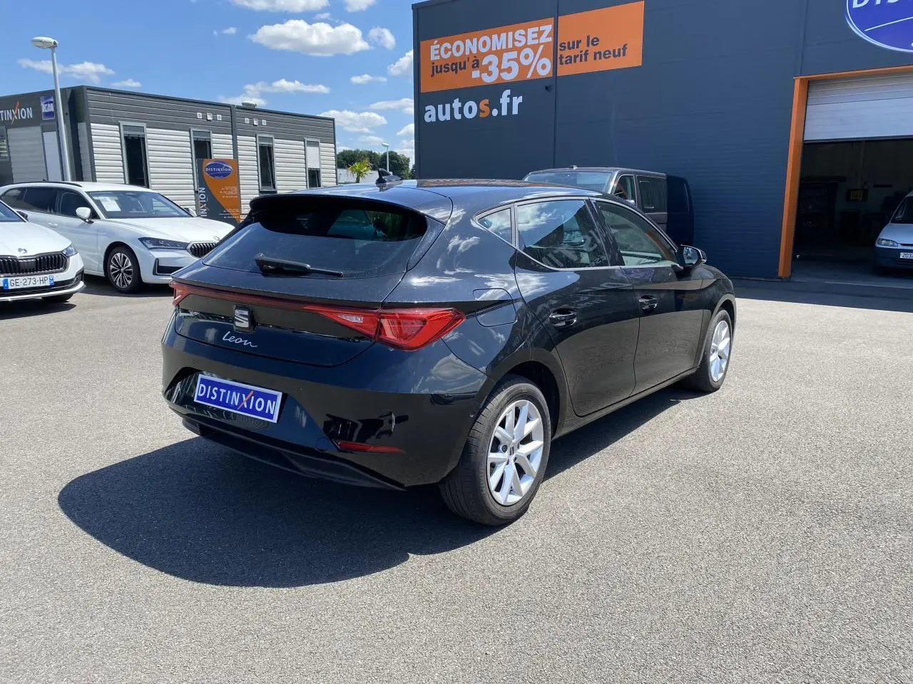 Vue 3/4 arrière droite d'une SEAT Leon 2024 noir Midnight avec vitres arrière surteintées sur parking extérieur.