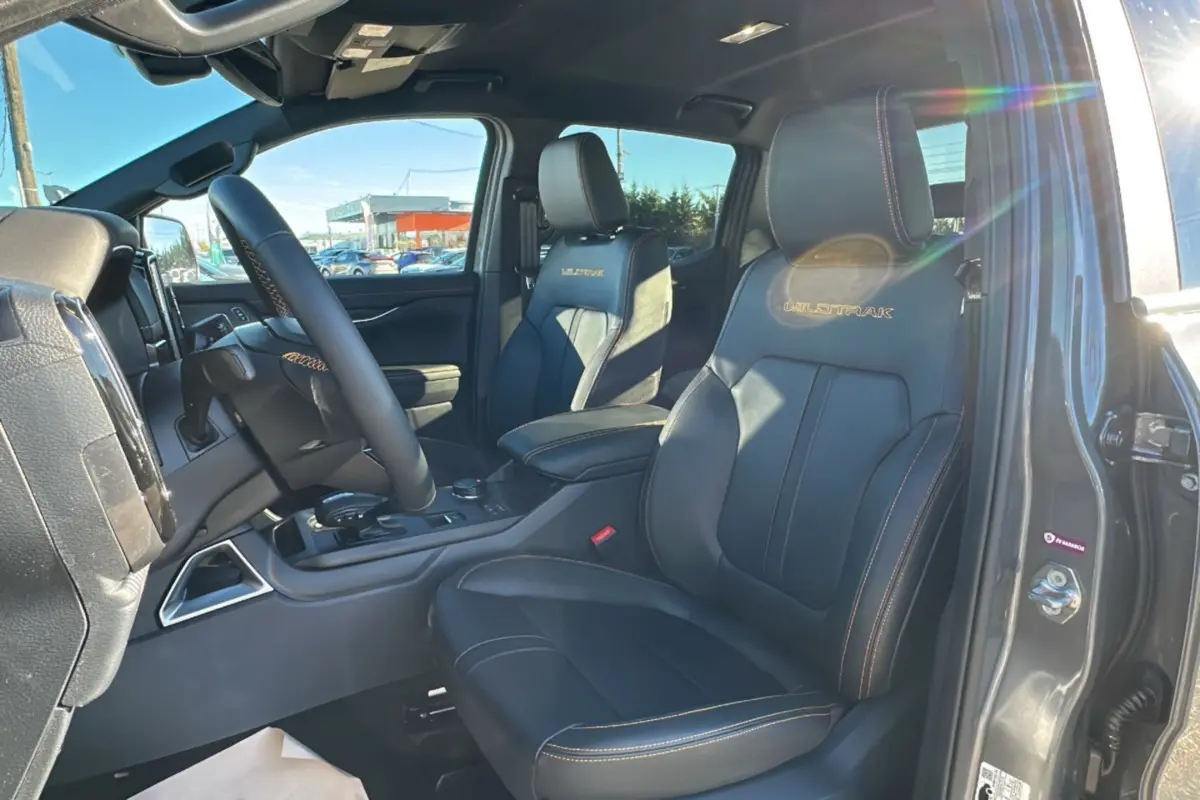Intérieur du Ford Ranger Wildtrak gris carbone, vue côté conducteur sur sièges cuir noirs avec logo Wildtrak brodé.
