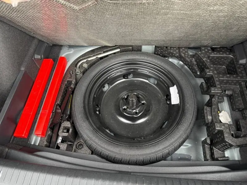 Vue plongeante sur la roue de secours noire dans le coffre d'une CUPRA Formentor 1.5 eTSI Hybrid 2025 gris magnétique mat.