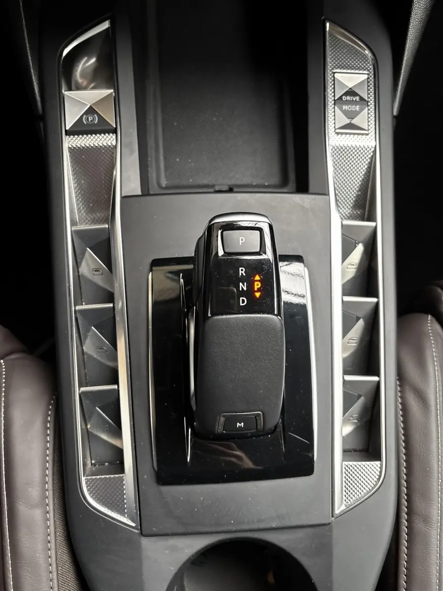 Vue plongeante sur la console centrale noire du DS3 2024, avec levier de vitesses automatique et boutons en finition métal brossé.