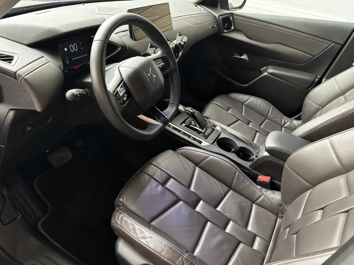 Vue intérieure côté conducteur du DS3 2024 avec sièges cuir gris foncé et tableau de bord digital moderne.