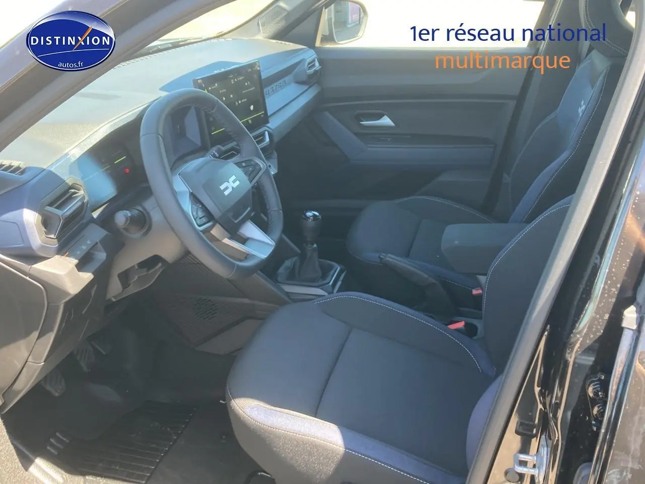 Intérieur noir du Dacia Duster 2025 vu côté conducteur, avec volant multifonction et boîte manuelle.