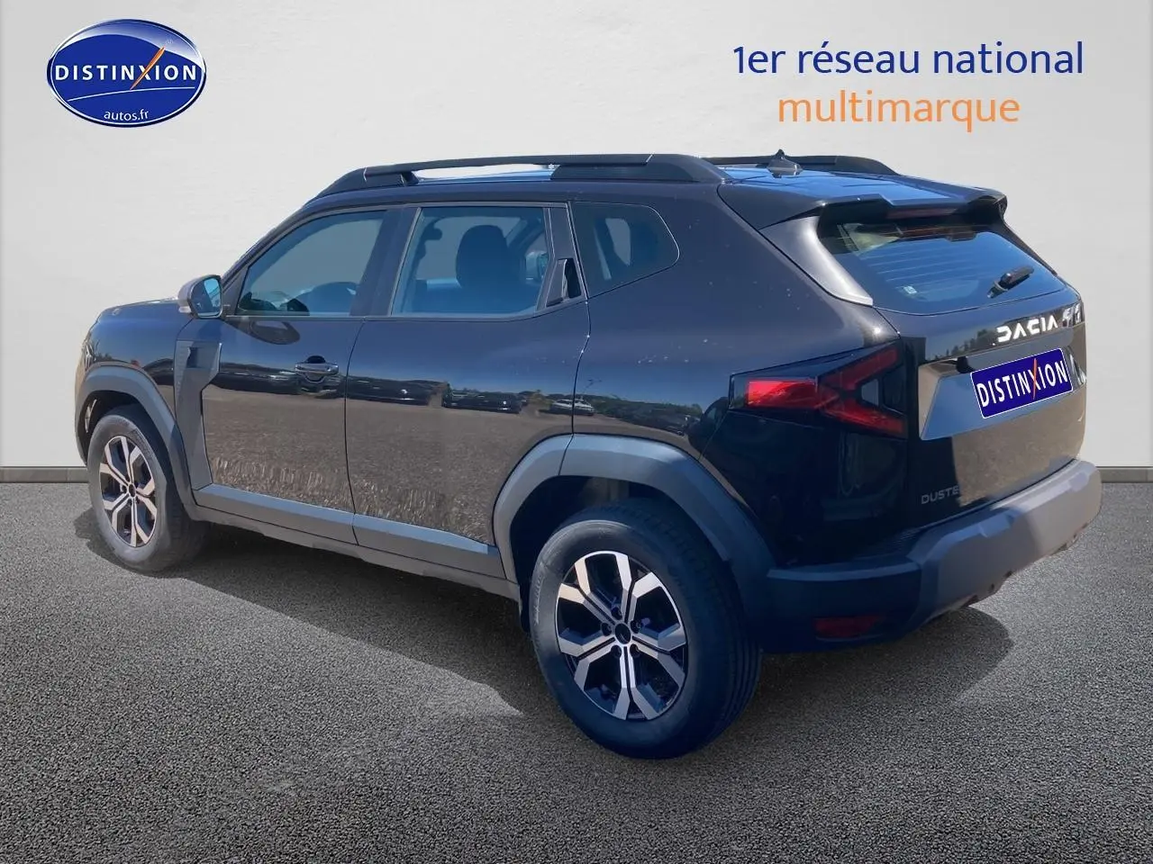 Vue 3/4 arrière droite du Dacia Duster noir 2025 avec jantes alu et barres de toit visibles.