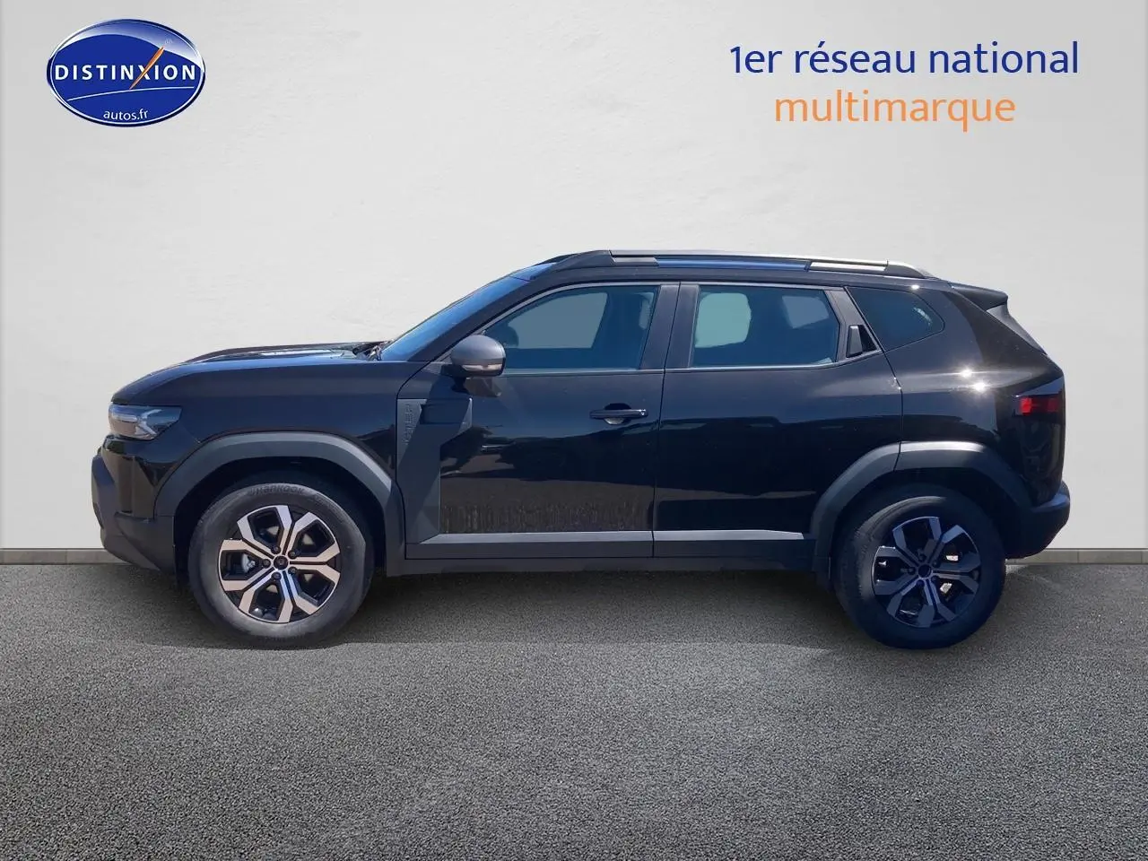 Profil droit d'un Dacia Duster noir 2025 avec jantes alu et barres de toit visibles sur fond neutre.