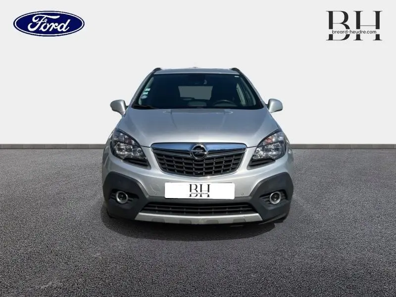 Vue avant d'un Opel Mokka gris minéral 2016 avec calandre chromée et phares halogènes visibles.