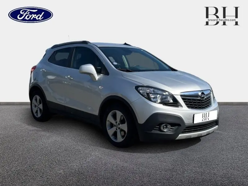 Opel Mokka gris minéral en 3/4 avant droit, avec calandre chromée et jantes alliage visibles.