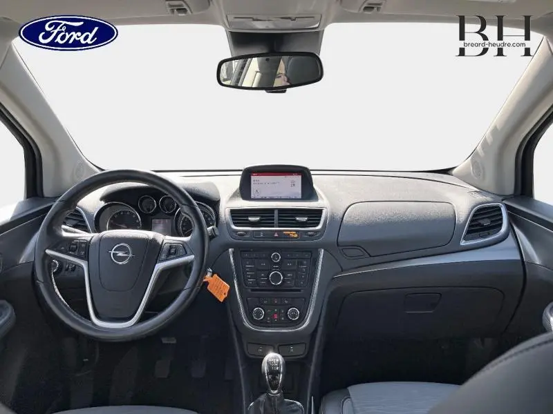 Vue intérieure avant de l'Opel Mokka gris Minéral 2016, volant multifonction et écran central visible.